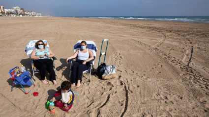 varias personas toman el sol en la playa de Gandía (Valencia)