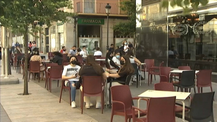 Clientes consumiendo en la terraza de un bar.