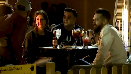 Jóvenes tomando una bebida en la terraza de un bar de noche