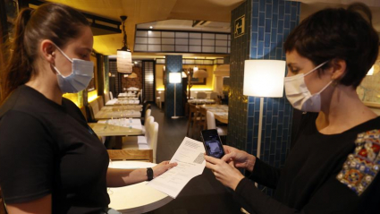 Una metre de un restaurante bilbaíno realiza una comprobación de un pasaporte Covid