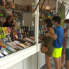 Varias personas viendo libros en una caseta de la feria del libro