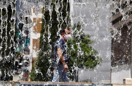 un hombre pasea con mascarilla cerca de una fuente