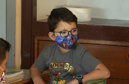 Niño sentando en su pupitre en el primer día de clase durante la pandemia