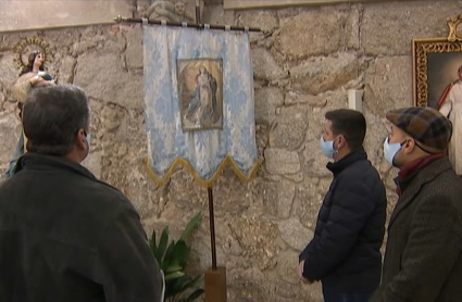 Mayordomos de 'Los escobazos' mirando el estandarte de la Virgen.