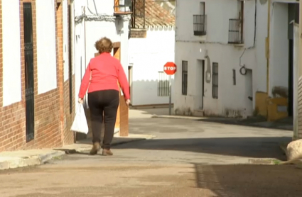 Mujer con bolsa de la compra por la calle de un pueblo