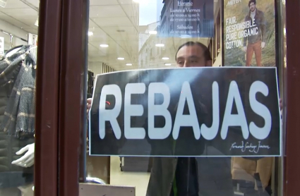 Colocando el cartel de rebajas en una tienda de Plasencia.