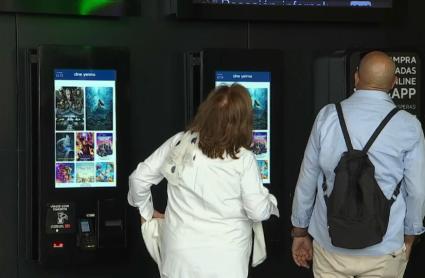 Una pareja de jubilados mira la cartelera de un cine en Badajoz 