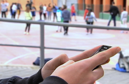 alumno usando móvil en el recreo